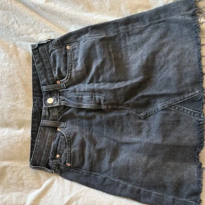 Grå jeanskjol med fransad kant - Snygg grå jeanskjol med fransad kant och klassisk femficksdesign. 