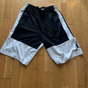 Svarta och vita shorts från Jordan - Snygga och sportiga shorts från Jordan i svart och vitt. De har en elastisk midja och ett stilrent märke på benet. Perfekta för träning eller en avslappnad dag.