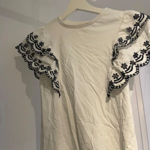 Vit blus - Vit topp med volanger. Kan stryka den eftersom den är lite skrynklig just nu!! 