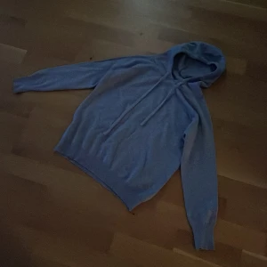 Grå merinoull hoodie - Säljer en bekväm grå hoodie med långa ärmar och justerbar huva. Perfekt för en avslappnad stil.    Den är gjord av merinoull.