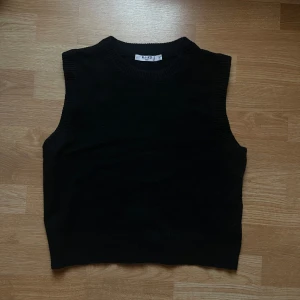 Svart stickad väst  - Snygg enkel svart stickad väst från Na-kd. Perfekt för lager-på-lager-stil eller över en vit skjorta som ger en stilren look. Passar utmärkt till både vardag och mer uppklädda tillfällen. Endast använt 1-2 gånger
