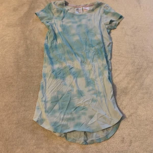 Blå och vit klänning - Säljer en blå och vit pyjamas klänning med korta ärmar och ett mjukt mönster. Pyjamasen har en rund hals och är tillverkad i ett lätt material, perfekt för varmare dagar.