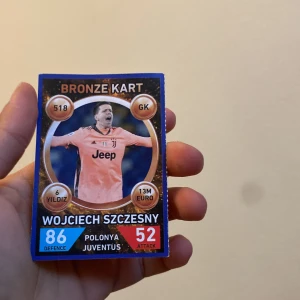 Fotbollskort med Wojciech Szczesny - Fotbollskort med Wojciech Szczesny i Juventus-tröja. Kortet är märkt 'Bronze Kart' och visar statistik som 86 i försvar och 52 i attack. Perfekt för samlare av fotbollskort!