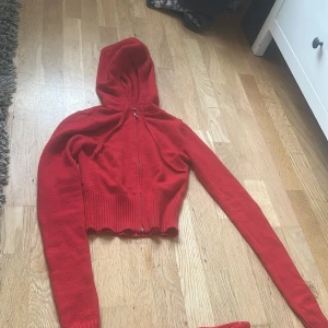 Röd croppad hoodie med byxor - Säljer en röd croppad hoodie med dragkedja och matchande byxor. Hoodien har långa ärmar och ribbade detaljer vid ärmslut och nederkant. Perfekt set för en avslappnad stil.🩷