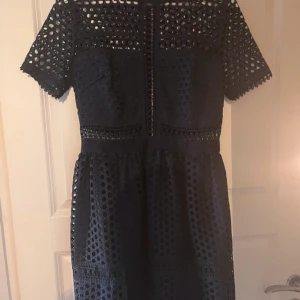 Blå klänning från By Malina - Snygg blå klänning från By Malina modellen Emily med korta ärmar och ett unikt hålmönster. Klänningen är i jätte bra skick och passar jätte bra till skolavslutning osv.