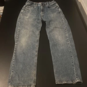 Blå jeans från Lindex - Säljer ett par klassiska blå jeans från Lindex. De har en straight passform med justerbar midja. Perfekta för en avslappnad stil. Jeansen har fickor både fram och bak.
