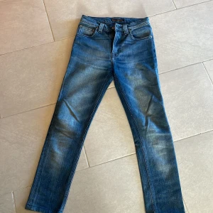 Blå jeans från Nudie Jeans - Snygga blå jeans från Nudie Jeans med klassisk femficksdesign och en bekväm passform. Jeansen har en dragkedja och knapp framtill samt Nudie-logga på bakfickan. Perfekta för en stilren look.  Säljer dem för 300kr