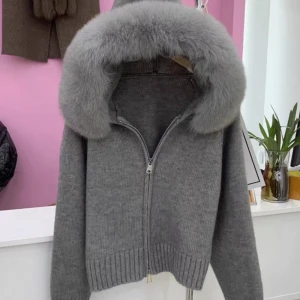 Grå stickad jacka med pälskrage - Snygg grå stickad jacka med en lyxig pälskrage. Jackan har dragkedja framtill och ribbade muddar vid ärmslut och nederkant💗Perfekt för kyliga dagar💗Säljer då den är en aning för kort för mig💗 skulle uppskatta den som en S elr lite mindre💗 inte äkta päls och fluffet sitter fast med knappar runt luvan så det går att ta av, men det innebär också lite glapp mellan luvan och fluffet, men det syns inte när man bär jackan💗 säljer för 300💗aldrig använd, endast testad💗