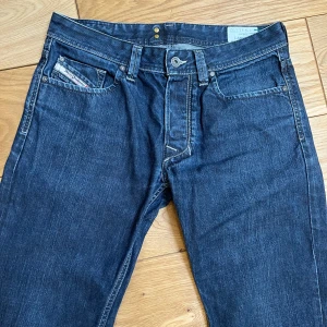 Mörkblå jeansbyxor - Snygga mörkblå jeansbyxor med klassisk femficksdesign och knappgylf. Perfekta för en avslappnad stil. De har en rak passform och är tillverkade i slitstarkt denim.