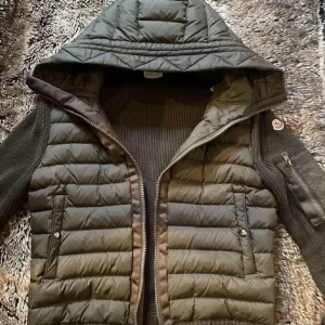 Monclear Cardigan - Snygg grön dunväst från Moncler med huva och dragkedja. Västen har två fickor med knappar framtill och en ärmficka med dragkedja. Perfekt för kyligare dagar.