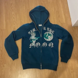 Blå hoodie med glittrigt tryck - Säljer en blå hoodie från Aim for the Moon med ett glittrigt tryck på framsidan. Hoodien har dragkedja och långa ärmar, perfekt för en cool och avslappnad stil. 🌀✨