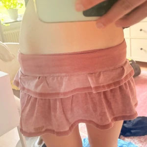 Rosa kjol från Superdry - Säljer en söt rosa kjol från Superdry med volangdetaljer. Kjolen har en elastisk midja och är perfekt för en avslappnad stil. Den är kort och har en mjuk känsla, vilket gör den bekväm att bära. Perfekt för varma dagar!