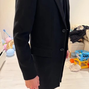 Svart kavaj med knappar - Snygg svart kavaj med klassiska knappar fram och på ärmarna. Perfekt för en stilren look. Passar bra till både vardag och mer formella tillfällen. Passar perfekt i S storlek. Jag rekommenderar den varmt.