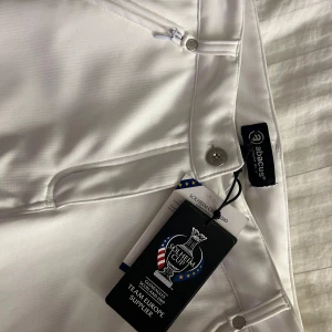 Vita byxor från Abacus - Snygga vita byxor från Abacus med dragkedja och knappdetaljer. Perfekta för en stilren look. Byxorna har en klassisk passform och är tillverkade i ett bekvämt material.