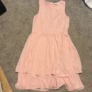 Rosa ärmlös klänning - Säljer en söt rosa ärmlös klänning. Klänningen har en fin lager-på-lager design med en lätt och fladdrig kjol. En väldigt fin rosa färg som är perfekt på sommaren💕
