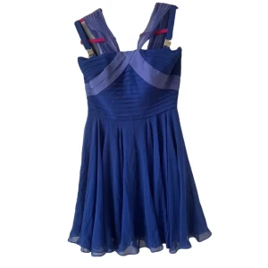 Blå klänning från Versace Collection - Snygg blå klänning från Versace Collection med veckade detaljer och breda axelband. Klänningen har ett feminint snitt och ett vackert fall – perfekt för en elegant kväll eller speciellt tillfälle. Tillverkad i Italien med högkvalitativt material. Köpt i Paris.