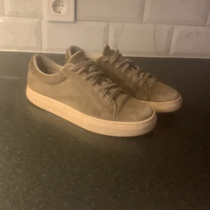 Beige mocka sneakers - Snygga beige sneakers i mocka med rund tå och snörning. Perfekta för en stilren look. Sulan är i en ljusare nyans som ger en fin kontrast till det övre materialet.