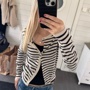 Randig kofta i beige och svart💋 - Säljer en stilren randig kofta i beige och svart. Koftan har långa ärmar och knappar framtill. Perfekt för en avslappnad look.