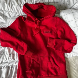 Röd hoodie från Peak Performance - Säljer en snygg röd hoodie från Peak Performance. Den har en klassisk design med en stor ficka framtill och justerbar huva. Perfekt för en avslappnad stil. Passar bra till både jeans och joggers.