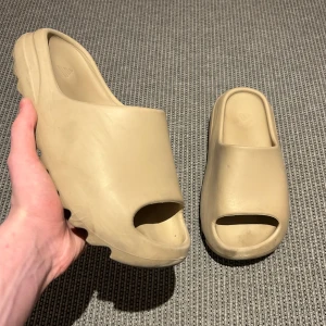 Yeezy slides - Säljer dessa riktigt feta yeezy slidsen perfekt för sommaren! Skorna är äkta och i bra skick. Färgen heter bone. För minsta fundering, hör av dig👍🏻