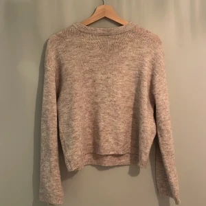 Beige stickad tröja från 157 - Säljer en mysig beige stickad tröja från 157. Tröjan har en enkel design med långa ärmar och ribbade kanter vid hals, ärmslut och nederkant. Perfekt för kyliga dagar!