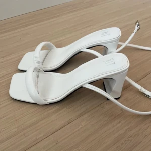 Vita klackar - Vita klackar, ca 6 cm höga Använda en gång och har små missfärgningar på bandet vid tårna som syns på bilden  Perfekta till t.ex studenten!