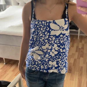 blå och vit blommig topp💙 - en tunn och löst sittande blå och vit blommig topp från Lindex i storlek xs. använt ca 2-4 gånger. svalt plagg till sommaren 🥰går att justera på baksidan!