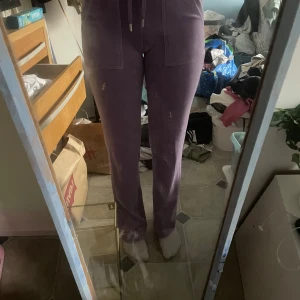 Lila mjukisbyxor från Juicy Couture - Säljer ett par lila mjukisbyxor från Juicy Couture. Byxorna har en bekväm passform med dragsko i midjan och är perfekta för en avslappnad stil. De är tillverkade i ett mjukt material som känns skönt mot huden.