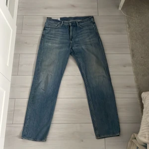 Blå jeans från &Denim - Säljer ett par blå jeans från &Denim i relaxed fit. De har en klassisk femficksdesign och är tillverkade i denim. Perfekta för en avslappnad stil.