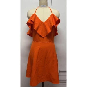 Orange klänning med volangdetalj - Snygg orange klänning med volangdetalj framtill och korsade band i ryggen. Perfekt för sommarens fester. Axelbandslös design med knytning i ryggen för en justerbar passform.