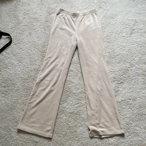 Beiga mjukisbyxor från H&M, strl 146 - Supermjuka och sköna beiga mjukisbyxor från H&M i storlek 146. Byxorna har en loose fit med raka ben och resår i midjan och även utsvängda nertill. Tillverkade i stretchig polyesterblandning med sammetslen yta för extra komfort.Perfekt för en chill dag hemma.🍿💓