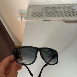 Svarta Ray-Ban boyfriend solglasögon - Klassiska svarta Ray-Ban boyfriend RB4147 med bred båge och mörka glas. Snygg och tidlös design med Ray-Ban-logga på sidan och framtill. Perfekta för att ge en cool vibe till din stil. Modellnummer RB4147, storlek 60-15. Perfekt nu när sommaren är igång