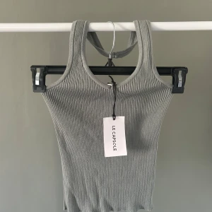 Grå ribbad linnetopp Le Capsule - Snygg grå ribbad linnetopp från Le Capsule. Toppen är ärmlös med breda axelband och har en tight passform. Perfekt att styla med jeans eller kjol för en clean look.