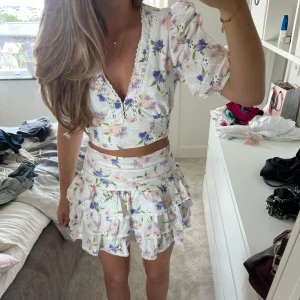 Det från Zara  - Supersött set i vitt med blommigt mönster i lila, rosa och grönt. Kjolen har flera volanger och hög midja, samt dragkedja . Toppen är stretchig! Säljer endast för ett bra pris☺️❤️