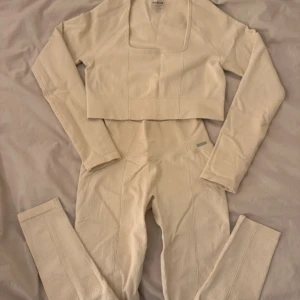 Cremefärgad set Aim'n - Cremefärgad set från Aim'n med fyrkantig ringning. Tillverkad i ett strukturerat, stretchigt material som passar perfekt till träning. Stilren och bekväm modell med tight passform.