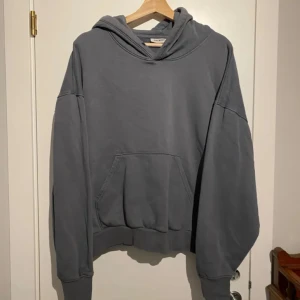 Grå hoodie från Weekday! S - Säljer en stilren grå hoodie från Weekday. Den har en klassisk design med en stor ficka framtill och en bekväm huva. Perfekt för en avslappnad look.Oversize. Snöret saknas. Inga skador eller anmärkningar. Jättefin! Mörkgrå