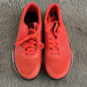 Koralrosa Reebok sneakers strl 38 - Snygga korallrosa sneakers från Reebok i storlek 38. Skorna har ventilerande mesh-ovandel, klassisk snörning och svartvit sula. Perfekta för träning eller en sportig look. Lätta och flexibla med modern design och Reebok-logga på sidan. Det är mammas gamla och hon säger att de knappt är använda.
