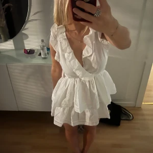 Vit volangklänning från Nelly - Helt ny med lappen kvar! Nypris 400kr mitt pris 300kr. Supersöt vit kortklänning från Nelly med volanger, omlott framtill och öppen rygg med knyt. Klänningen är ärmlös och har en luftig, somrig känsla. 