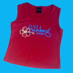 Croppad linnetopp  - Rött croppat linne med text och en blomma framtill. Står att det det är storlek L men passar mer som xs eller s.