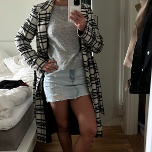 Jättefin kappa i ullmix - Snygg lång kappa i svartvitt rutigt mönster med klassisk krage och bälte i midjan. Jackan är fodrad och har en rak passform som ger en clean och trendig look. Perfekt för dig som vill sticka ut med en statement piece i höst och vinter🤍🤍