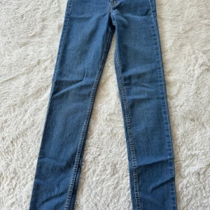 Blå skinny jeans från H&M - Snygga blå skinny jeans från H&M med regular waist och ankellängd. Klassisk femficksmodell i stretchig denim som sitter tight hela vägen ner. 