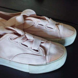 Ljusrosa sneakers stl 37 - Ljusrosa sneakers med satin finish och breda snören. De är sparsamt använda  men inte som nya, därav lågt pris. Perfekta för dig som har en söt stil med en touch av pastell.