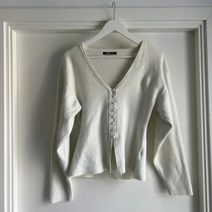 Vit kofta med knappar från Gina Tricot - Superfin vit kofta från Gina Tricot i mjukt material. Den har v-ringning, långa ärmar och snygga knappar framtill. Perfekt att slänga över en topp eller bära som den är. Enkel och stilren design som passar till allt.