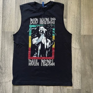 Bob Marley ärmlös t-shirt från H&M - Svart ärmlös t-shirt från H&M Divided i storlek M. Längden är 70 cm. Har haft på mig denna kanske bara en gång. 