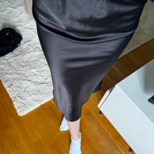 Satinkjol - Svart satinkjol från Nelly i storlek 36, passar typ XS-S. Lite skav/noppror vid höfterna (se sista bilden), annars bra skick. Kjolens längd är 75cm.
