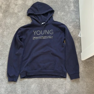 Mörkblå hoodie från Gina Tricot - Jag säljer den här snygga mörkblå hoodien från Gina Tricot med texten 'YOUNG' i silvriga detaljer framtill💞Hoodien är i storlek 158/164!