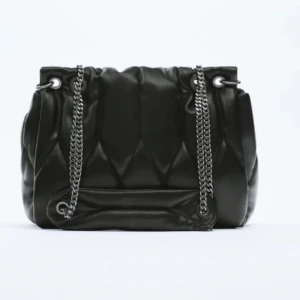 Svart quiltad axelväska - Stilren svart axelväska med quiltad design och silverfärgade kedjor som axelrem. Väskan är i nysick då den används endast ett par fåtal gånger.