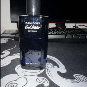 Davidoff Cool Water Intense parfym - Davidoff Cool Water Intense Eau de Parfum i en stilren, mörkblå glasflaska med svart kork. Flaskan har en modern, kantig design och rymmer en fräsch och maskulin doft som passar perfekt för dig som gillar klassiska parfymer.