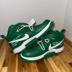 Nike X Off-White Air Force 1 Pine Green - Gröna Nike x Off-White Air Force 1 sneakers med vita detaljer och text på sidan. Skorna har robust sula med grönt mönster, vita skosnören och klassisk Off-White tag. Perfekt för dig som vill sticka ut med en unik och trendig sneaker.