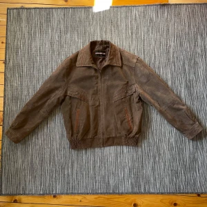 Brun mockajacka - Brun mockajacka från Charles Klein i storlek M. Knapparna på bröstet är bara design och inte fickor. Dock är fickorna längre ned på framsidan helt funktionella.